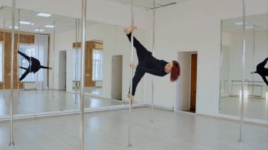 Siyah giysili genç pole dans kadın kendini pilon üzerinde poz tutamaz