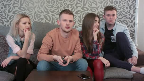 Grupp unga vänner titta på TV tillsammans på soffan hemma — Stockvideo