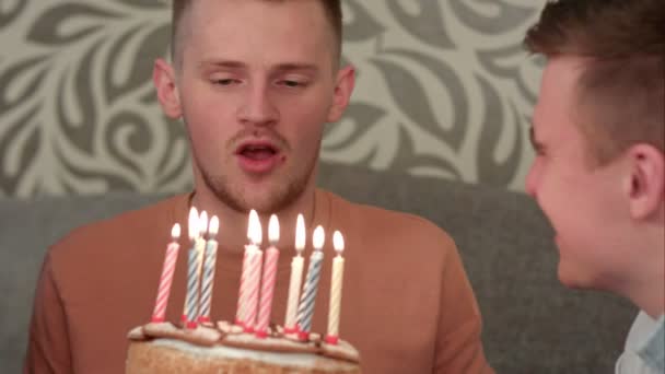 Chico guapo sueña con su deseo y sopla velas en pastel de cumpleaños y bebe juce naranja — Vídeos de Stock