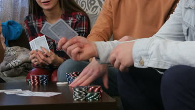 Öğrenci evinde masada oturan ve poker oyunu oynayan arkadaş şirket