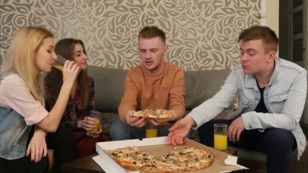 Молодые люди в повседневной одежде едят пиццу, разговаривают, смеются — стоковое видео