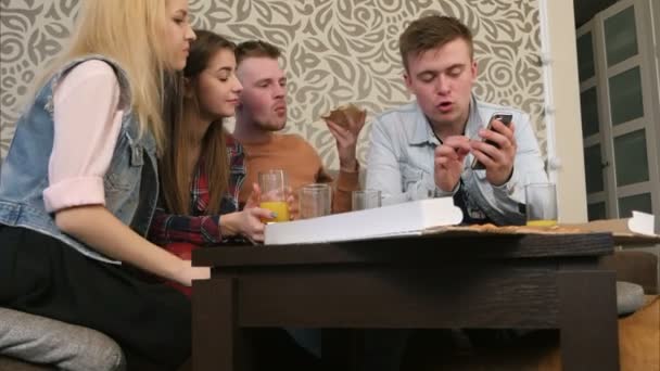 젊은 친구 들 피자 먹고 이야기 하면서 부스러기를 먹는 테이블 아래 빨간 고양이 — 비디오