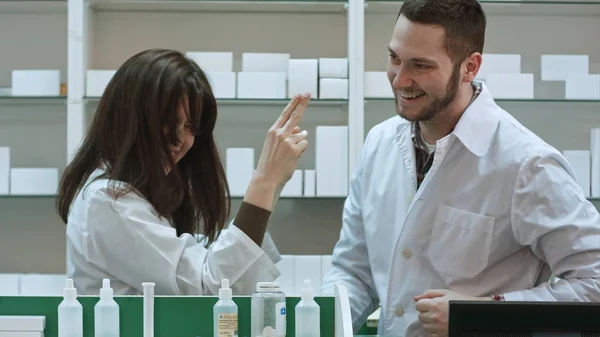 Jovem farmacêutico engraçado vestido de uniforme branco dançando na farmácia — Fotografia de Stock