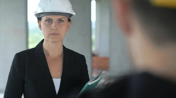 Uma mulher construção ouvindo é colega no prédio de escritórios — Fotografia de Stock