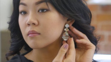 Young asian woman puts on beautiful earrings clipart