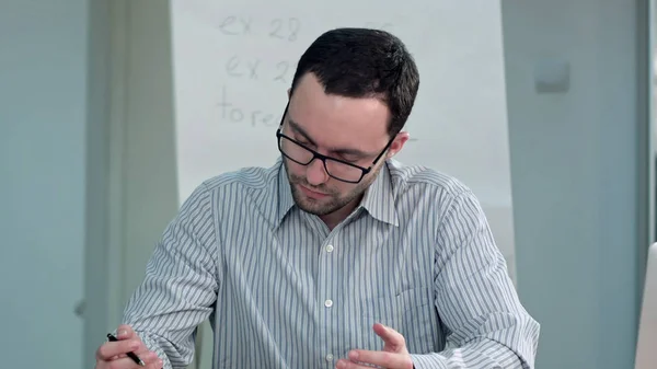 Professeur assis au bureau en classe et parler à un étudiant — Photo