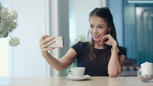 Усміхнена молода жінка бере селфі на свій телефон в кафе — стокове фото