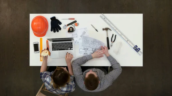 Architetto donna discutere disegno con il suo collega durante il pranzo e digitando — Foto Stock