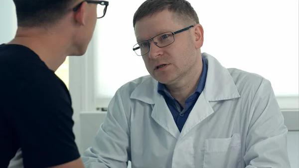 Чоловік лікар в окулярах консультує пацієнта чоловічої статі — стокове фото