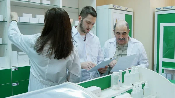 Équipe de pharmaciens vérifiant les documents et les médicaments à la pharmacie — Photo