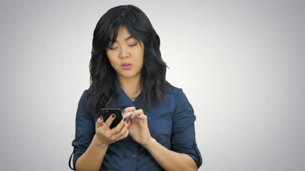 Pensivo asiático empresária leitura apresentação no smartphone, olhando para a câmera no fundo branco — Vídeo de Stock