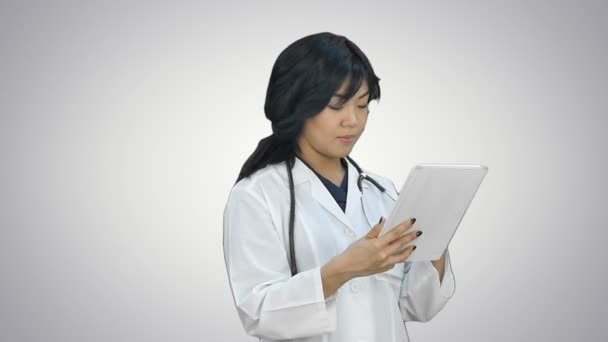 Aziatische arts vrouw met behulp van digitale tablet en glimlachend op witte achtergrond — Stockvideo
