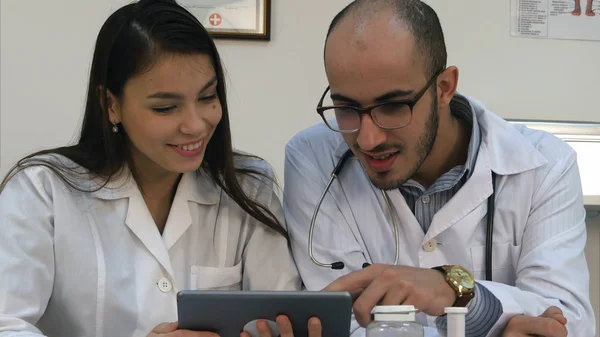 Dois médicos olhando para algo engraçado no tablet e rindo — Fotografia de Stock