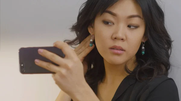 Азіатський жінка за допомогою смартфона виправлення її волосся і зробити вгору — стокове фото