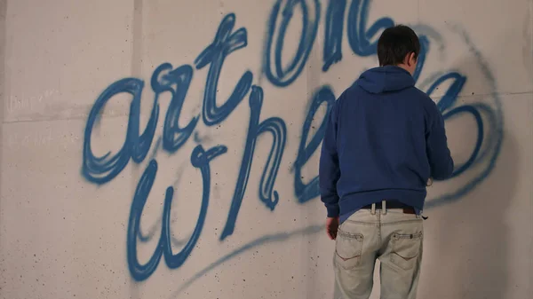 Joven dibujando graffiti en una pared con una lata de spray — Foto de Stock