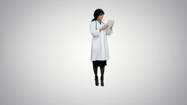 Mujer médica asiática mira tableta digital sobre fondo blanco — Vídeo de stock