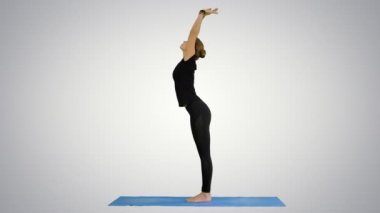 Genç kadının Yoga güneşi selamlama poz mat beyaz arka plan üzerinde yapması