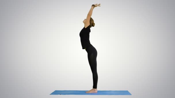 Mujer joven haciendo yogui sol saludo pose en la estera sobre fondo blanco — Vídeo de stock
