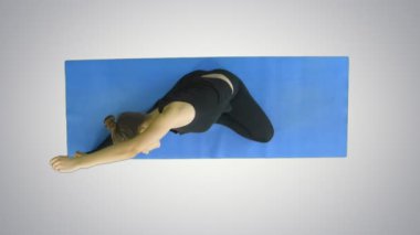 Genç kadın mat beyaz arka plan üzerinde bacak Germe yerleştirmek