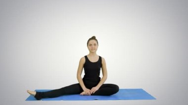 Genç kadın beyaz arka plan üzerinde yoga pratik yaparken bacaklarını germe