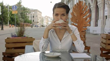 Kahve veya çay içme ve açık café'de dedikodu gülümseyen genç kadın