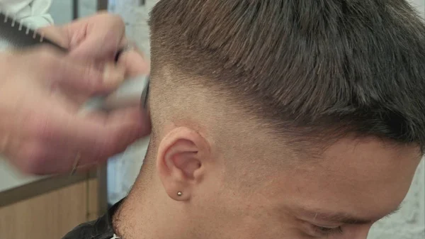 Hairdresser cutting with trimmer hair of man client at beauty parlour — Stock Photo, Image