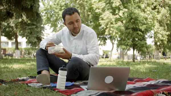 Hipster hombre de negocios bebiendo una taza de café en la cafetería de la ciudad durante la hora del almuerzo. Él está trabajando en el ordenador portátil y llamando por teléfono móvil . — Foto de Stock