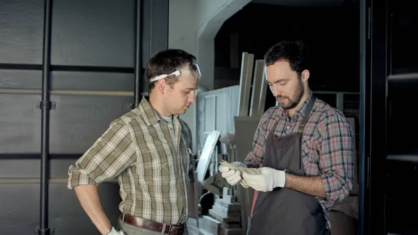 Dos carpinteros cuentan el dinero en el taller . — Foto de Stock