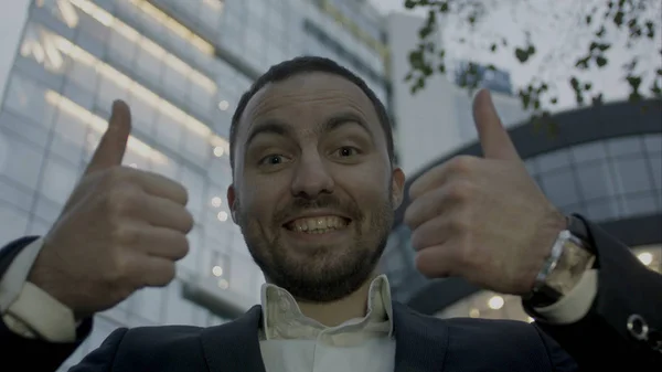 Dos pulgares arriba, retrato del joven hombre de negocios en el fondo del edificio de oficinas. Caucásico hombre con barba sonriendo . — Foto de Stock