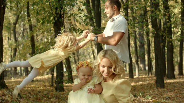 Father spinning his daughter in the autumn forest