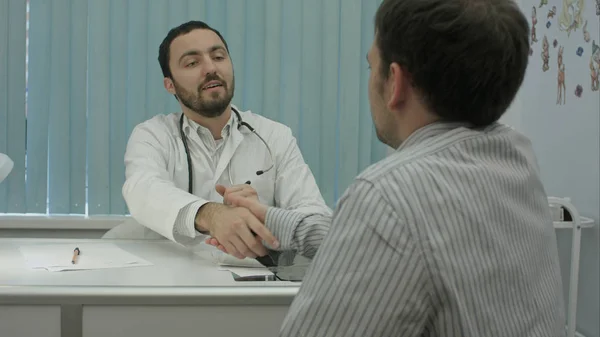Чоловічий бородатий лікар у клініці з чоловічим пацієнтом тремтить руками — стокове фото