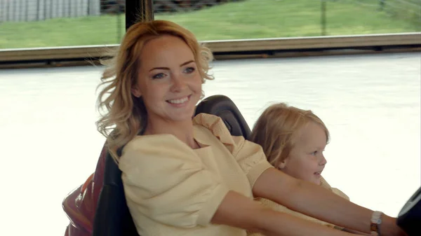 Sorridere madre con la figlia guidare su auto paraurti nel parco divertimenti — Foto Stock
