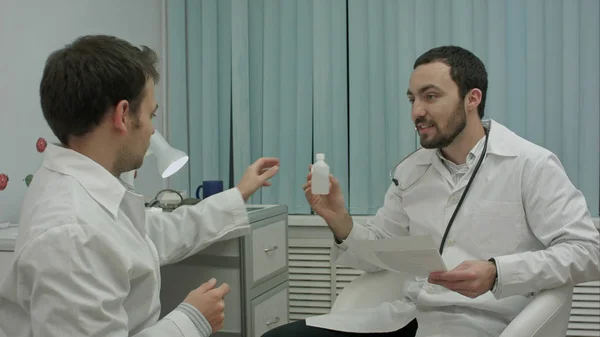 Bearded doctor shows new drugs to intern — Stock Photo, Image