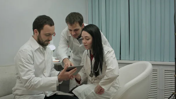 Команда лікарів дивиться щось смішне на планшетному ПК в медичному кабінеті — стокове фото