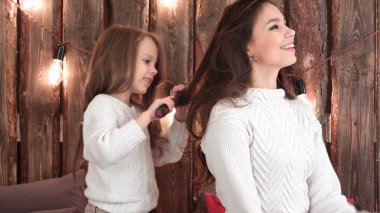 Kanepede oturan sevimli küçük kızı penye koyu saçlı anne