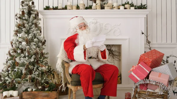 Papai Noel sentado em sua oficina lendo uma carta — Fotografia de Stock