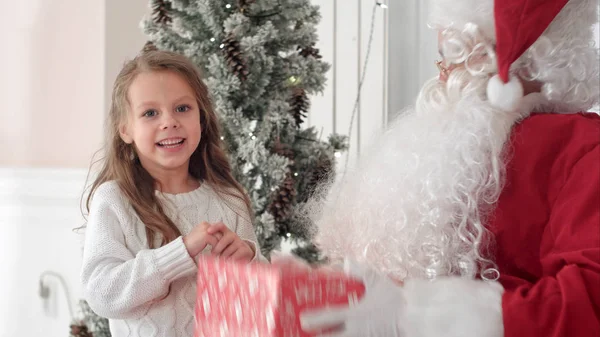 Papá Noel dando un regalo bien envuelto a una linda niña — Foto de Stock