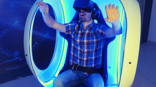 Podekscytowany młodego człowieka, ciesząc się wirtualnej rzeczywistości atrakcją na krześle vr — Zdjęcie stockowe
