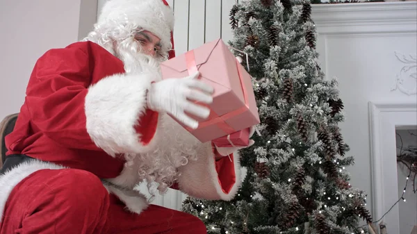 Mikulás zsákját megnyitása és üzembe bemutatja a karácsonyfa alatt — Stock Fotó