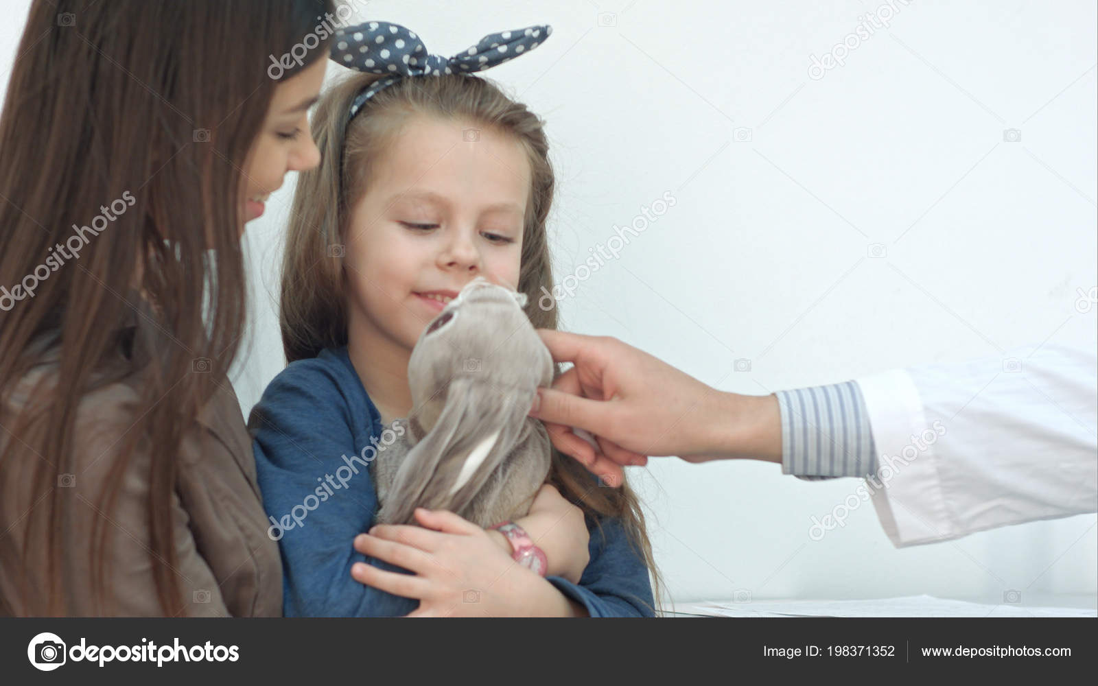 Doctor Trying To Cheer Up Little Girl Patient Hugging Her Bunny