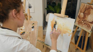 Genç kadın sanatçı beyaz tuval üzerine yağlı boya ile önlük resminde. Atış kapatın. Lumix Gh4 profesyonel vuruşta 4 k çözünürlüklü. Örneğin ticari video, işinizde, sunuyu kullanabilir miyim
