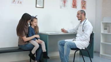 Çocuk doktoru Doktor muayene çocuk, annesi holding babygirl kucağında iken