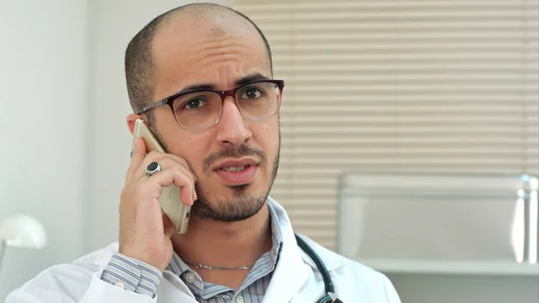 Joven doctor en gafas hablando por teléfono móvil —  Fotos de Stock