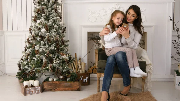 Mãe mostrando sua filhinha como digitar uma mensagem para o Papai Noel no telefone — Fotografia de Stock