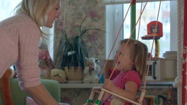 Anne ve çocuk salıncak üzerinde gülümseyen