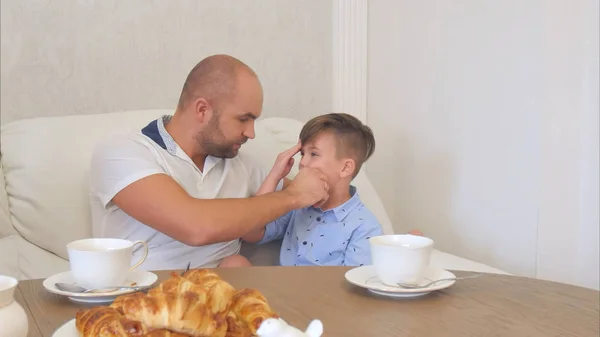 Młody ojciec czyszczenie twarzy mały syn po obiedzie — Zdjęcie stockowe