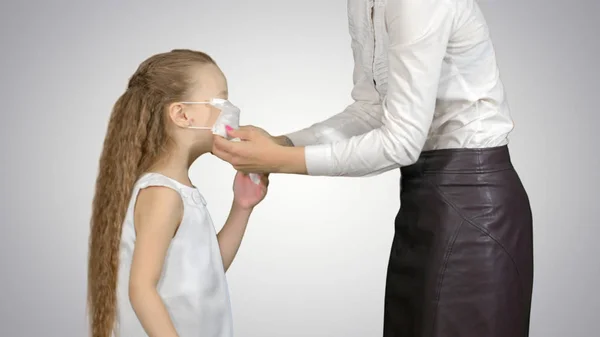 Mãe e filha usando máscaras cirúrgicas para proteger de uma epidemia em fundo branco — Fotografia de Stock