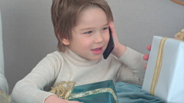 Un niño hablando por teléfono describiendo los regalos que recibió para Navidad. — Foto de Stock