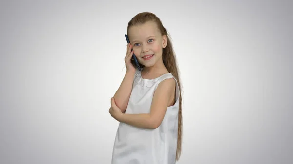 Menina bonito falando no telefone celular no fundo branco — Fotografia de Stock