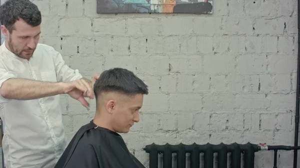 Grande momento al barbiere. Allegro giovane uomo barbuto ottenere taglio di capelli dal parrucchiere — Foto Stock